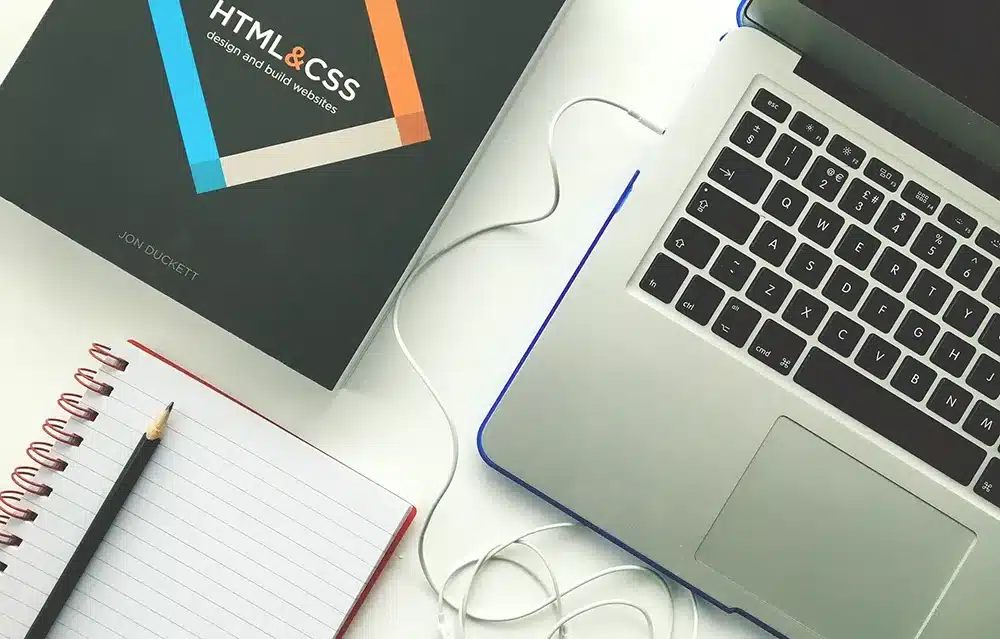top view of a desk with a keyboard, book and notebook on top
