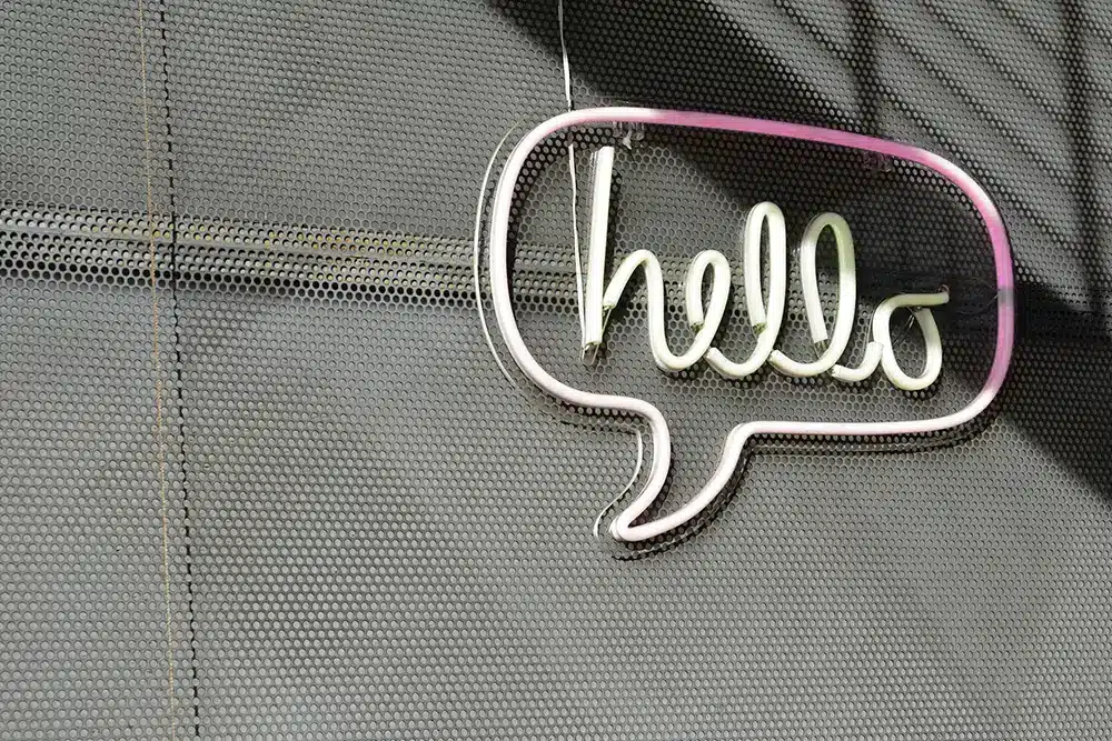 neon sign of a speech bubble that says "hello" against a black background