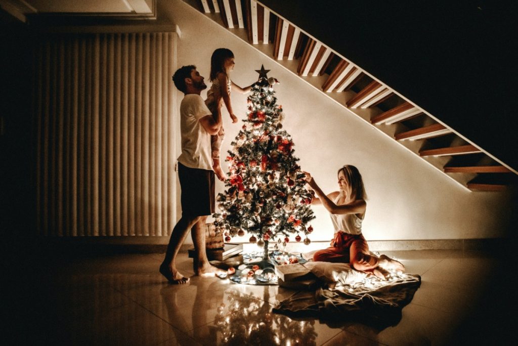 small family decorating christmas tree during covid-19
