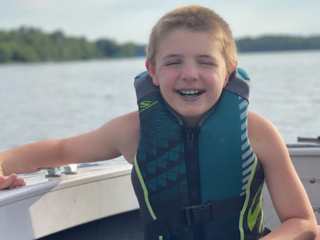 sam smiling on a boat while wearing a life jacket