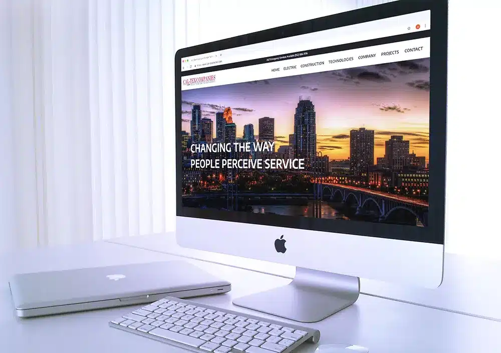 the cal-tex electric website homepage on a large computer monitor next to a laptop and keyboard