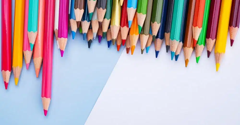 colored pencils in a variety of colors lying on top of a blue background
