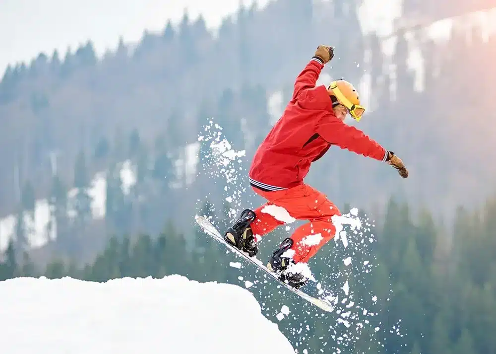 a snowboarder in midair jumping off a snowy mountain