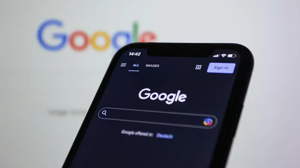 google on a phone screen with a computer screen of google behind it