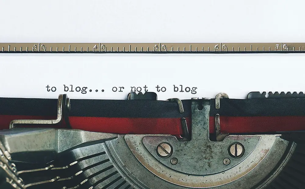 a top view of a typewriter that has "to blog or not to blog" typed out on a piece of paper